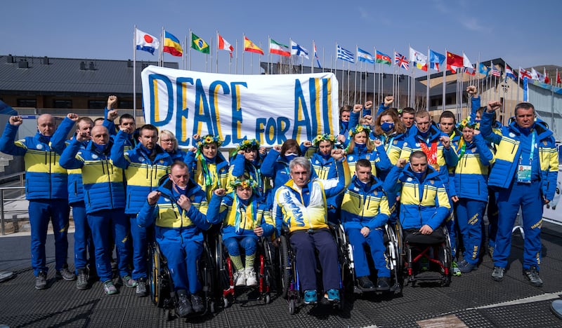 Valerii Sushkevych, president of the Ukraine National Paralympic Committee, and the Ukraine delegation raise their fists and pose with a banner at the Beijing 2022 Winter Paralympic Games. Reuters