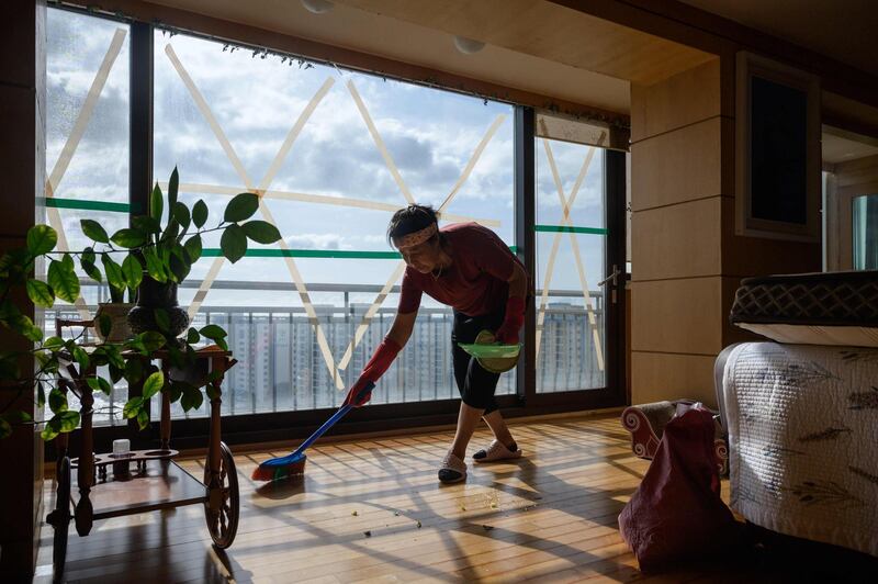 A woman cleans an apartment after strong winds from Typhoon Maysak left windows shattered, near Gwangalli beach in Busan.  AFP