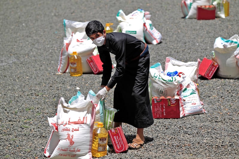 A Yemeni youth carries a portion of food aid, distributed by Yadon Tabney development foundation, in Yemen's capital Sanaa on May 17, 2020. (Photo by MOHAMMED HUWAIS / AFP)