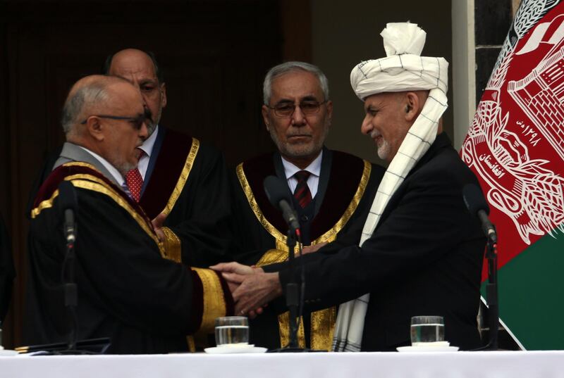 Afghan President Ashraf Ghani, right, shakes hands with Chief Justice Sayed Yousuf Halim. AP