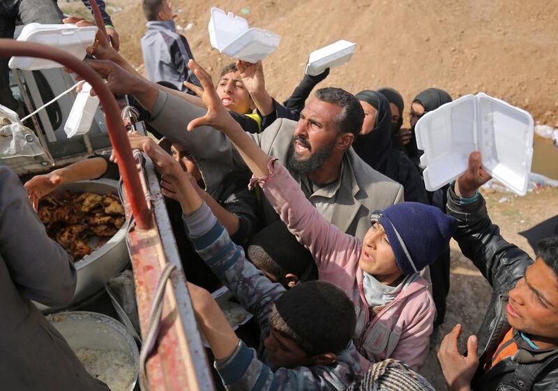 Iraqis displaced from the city of Mosul reach out to receive food aid at a camp in the Hamam Al Alil area south of the embattled city on March 11, 2017, during the government forces ongoing offensive to retake the area from ISIL. Ahmad Al Rubaye/AFP
