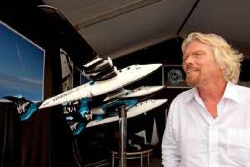With a model of WhiteKnightTwo behind him, Sir Richard Branson, gives an interview Monday July 27, 2009 at the Experimental Aircraft Association's annual AirVenture convention in Oshkosh, Wis.  British billionaire Sir Richard Branson hopes to use WhiteKnightTwo to carry a spaceship into the upper atmosphere. The spaceship would then detach and rocket into space. Branson hopes to use the system to create a commercial space travel business.  (AP Photo/Mike Roemer) *** Local Caption ***  WIMR109_Space_Plane.jpg