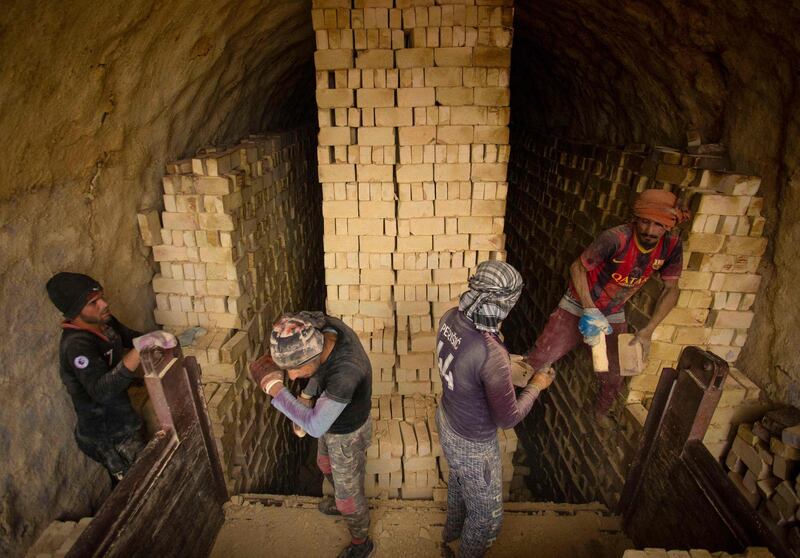 Workers stack bricks at the small factory.  AFP