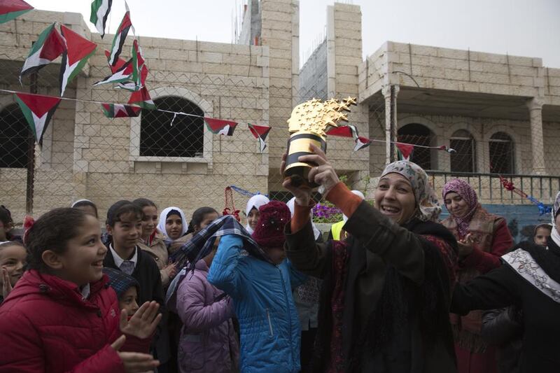 Palestinian teacher Hanan Al Hroub shows her Global Teacher trophy to Samiha Khalil students and teachers on March 20, 2016, who welcomed her back on March 20,2016. Heidi Levine for The National