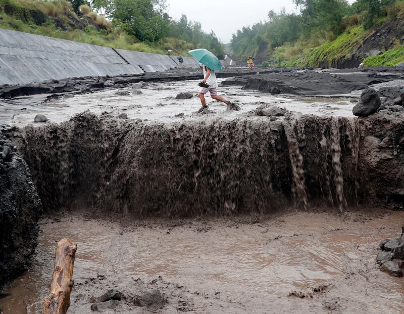 A Filipino villager traverses a river following a flash flood at the slope of the rumbling Mayon Volcano in the town of Daraga, Albay province, Philippines. Francis Malasig / EPA