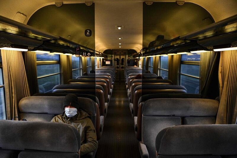 A man wearing a protective face mask sits in an almost-empty carriage of a train arriving in Paris on March 17, 2020. AFP