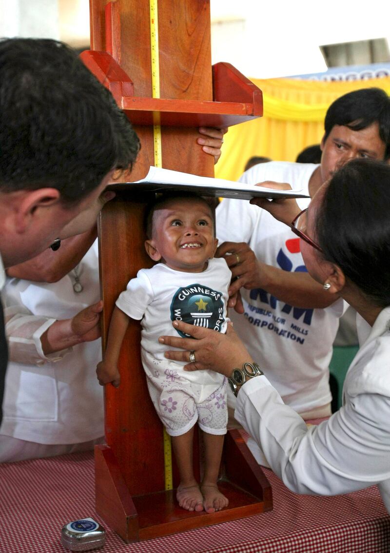 Junrey Balawing, center, smiles as he is measured by Guinness World Records adjudicator Craig Glenday, left, for the last of a series of measurements conducted at Sindangan Municipal Hall, Sindangan township, Zamboanga Del Norte province in Southern Philippines, Sunday June 12, 2011, his 18th birthday and coincidentally the Philippines' Independence Day. Balawing was officially declared 'the world's shortest living man' with a measurement of 23.5 inches (59.93 centimeters) dislodging Nepal's Khagendra Thapa Magar with a measurement of 26.4 inches. (AP Photo/Bullit Marquez) *** Local Caption ***  XBM105_APTOPIX_Philippines_Shortest_Man.jpg