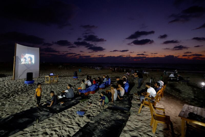 Palestinian families watch a broadcast on a large projector screen at a beachfront cafe during a rare cinema event in Gaza city. Reuters