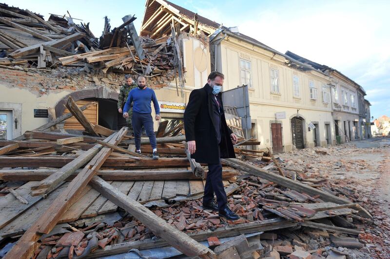 People move through remains of a building damaged in an earthquake, in Petrinja, Croatia.  AP