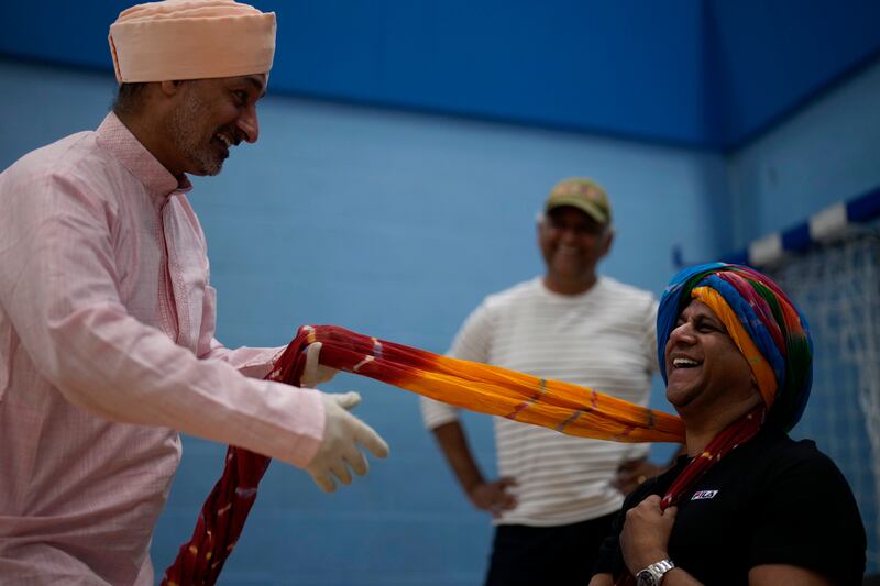 A performer ties another's turban at rehearsals. AP Photo
