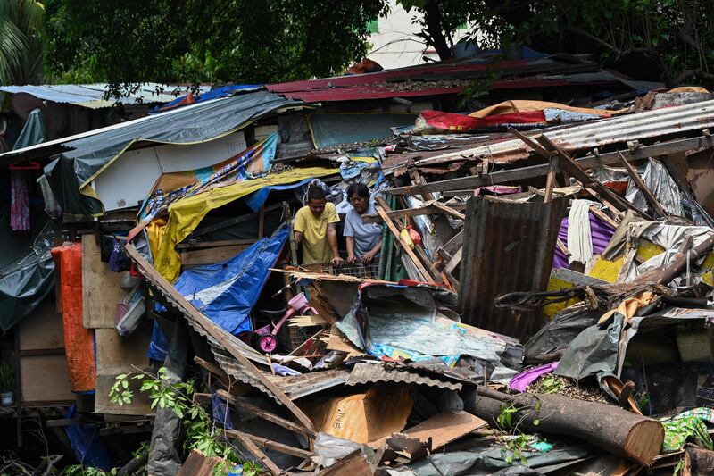 Residents inspect the damage after a huge tree fell on a settlement in Manila, the Philippines. Two people were killed. AFP