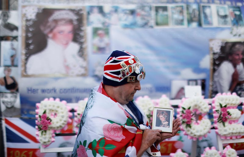A man holds a photo of Princess Diana, during a gathering outside Kensington Palace, in central London, on the 25th anniversary of the Princess of Wales's death. Flowers and other tributes were laid at the princess's former London home and above the Paris road tunnel where she lost her life, to mark the day. AFP