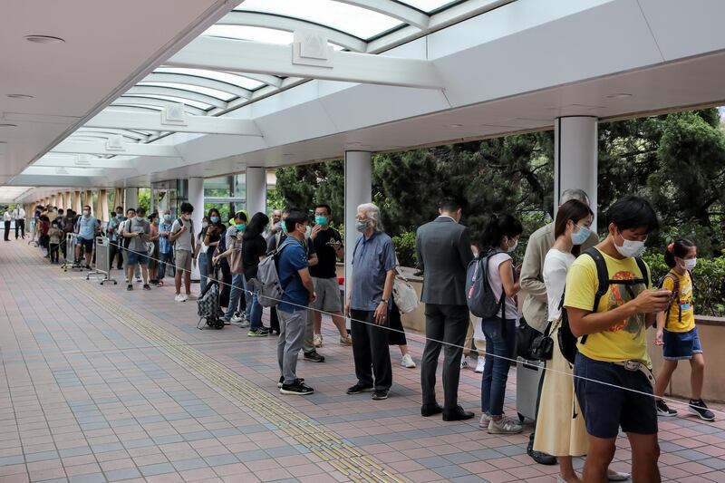 People wearing protective masks wait in line to enter the Central Library in the Causeway Bay district of Hong Kong. Bloomberg