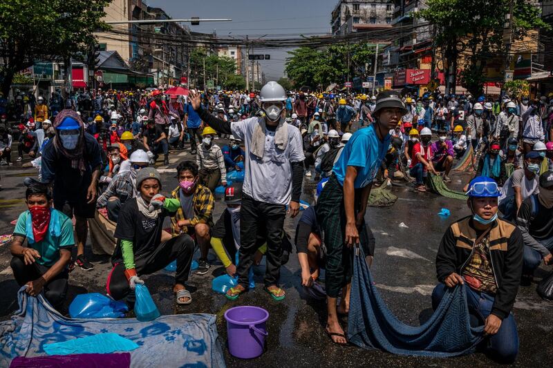 YANGON, MYANMAR - MARCH 01: Anti-coup protesters hold drenched sheets in preparation for the deployment of tear gas by riot police on March 01, 2021 in Yangon, Myanmar. Myanmar's military government has intensified a crackdown on protesters in recent days, using tear gas and live ammunition, charging at and arresting protesters and journalists. At least 18 people have been killed so far, according to monitoring organizations. (Photo by Hkun Lat/Getty Images)