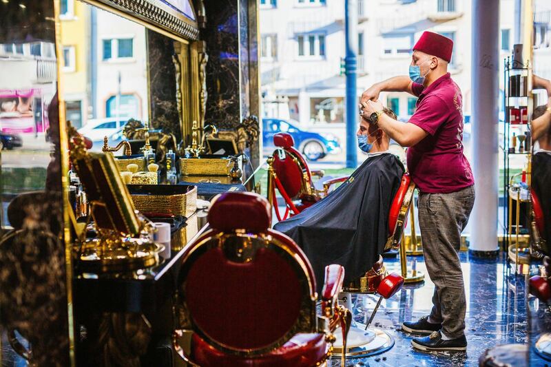 Muhammet 'Memo' Akbas cuts Aleksandar Petrovic's hair in a barber shop in Freiburg. AP Photo