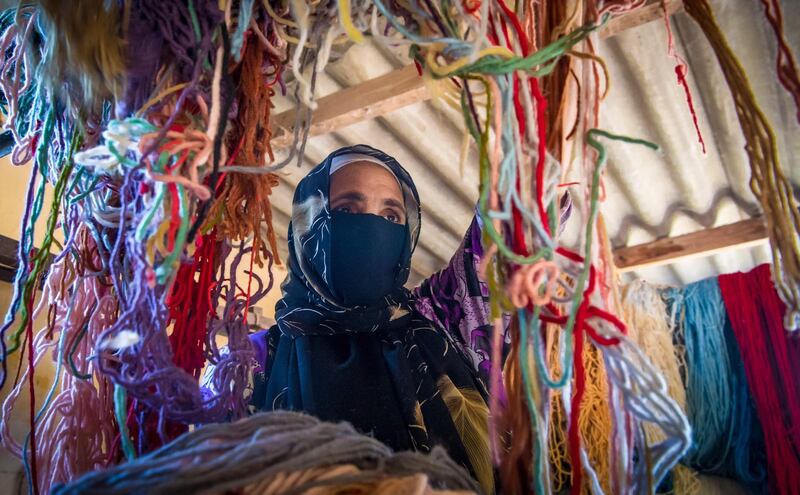 A Moroccan rug weaver sorts out yarn at a workshop in the city of Sale, north of the capital Rabat, on June 3, 2020, during the novel coronavirus pandemic.  Artisans in Morocco have been starved of income for almost three months because of the COVID-19 pandemic. The crafts industry represents some seven percent of GDP, with an export turnover last year of nearly 1 billion dirhams ($100 million). / AFP / FADEL SENNA
