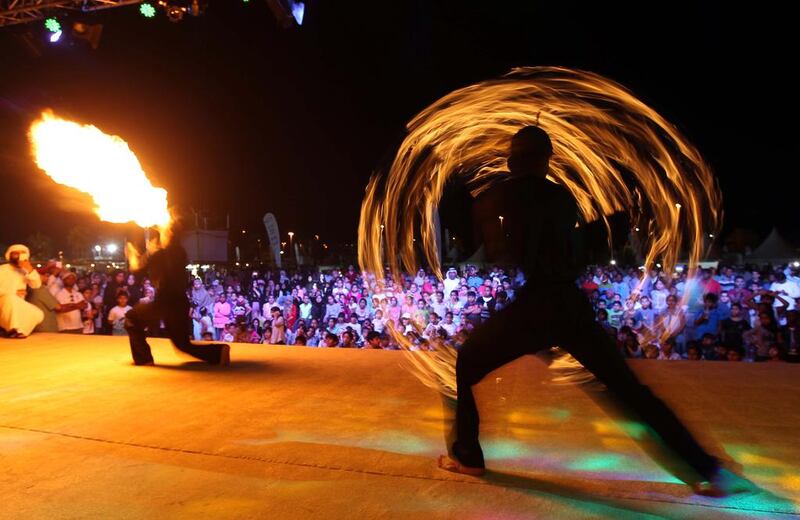 Visitors watch a fire performance on the open air stage at the Al Gharbia Watersports Festival.