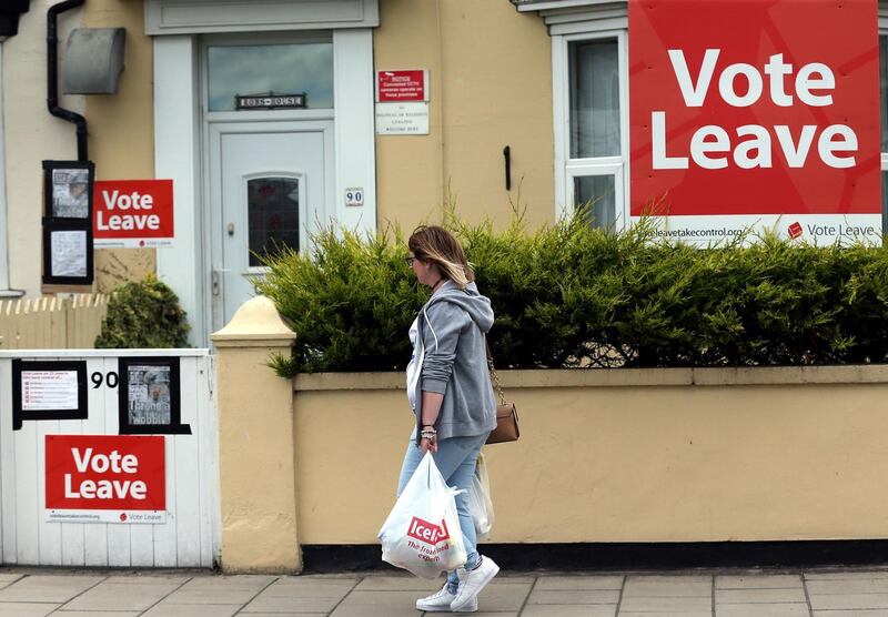 A woman walks past a house where 'Vote Leave' boards are displayed in Redcar. AFP