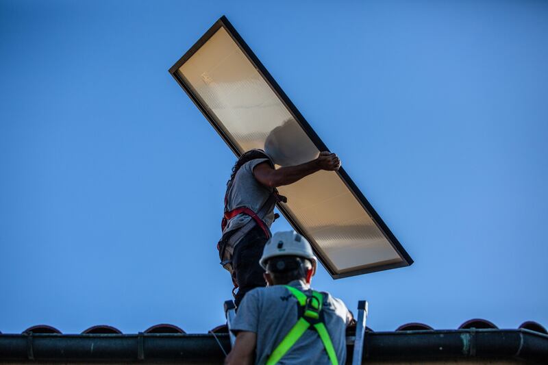 Engineers carry solar panels on to the roof of a property in Barcelona in September 2022. Spain and other Mediterranean countries have generated record amounts of power from wind and solar farms. Bloomberg