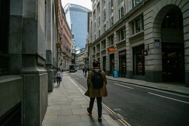 A pedestrian walks through a street City of London square mile financial district in London. The number of people claiming jobless benefits in the UK has risen to 2.7 million, an increase of 121 per cent since March. Bloomberg