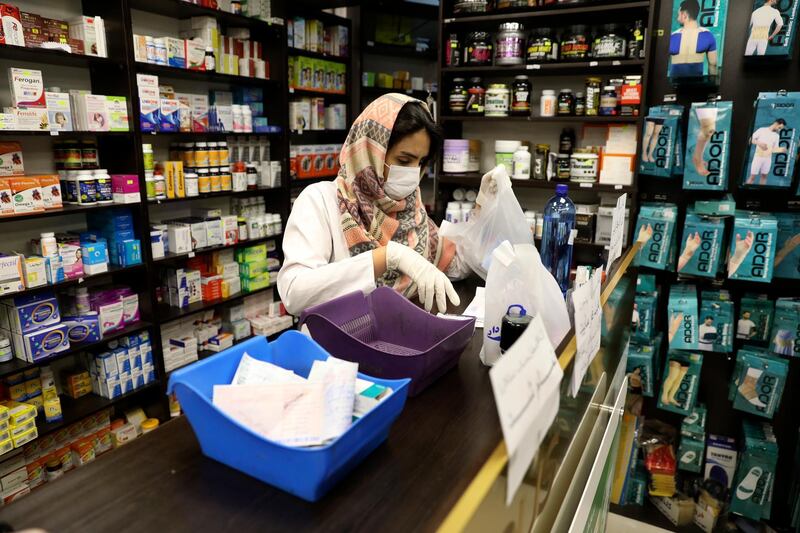 A pharmacist wearing a face mask works in western Tehran on Saturday. Iran is preparing for the possibility of "tens of thousands" of people needing to be getting tested. Vahid Salemi / AP Photo