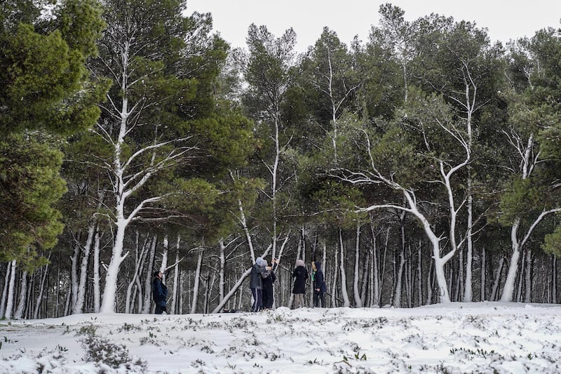 People pose for a picture in the snow outside a forest in the Sidi al-Hamri region of Libya's eastern Jebel Akhdar (Green Mountain) upland region, about 200 kilometres east of Benghazi, on February 16, 2021. (Photo by - / AFP)
