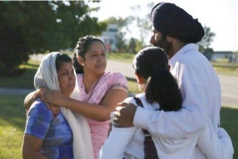 People console each other near the Sikh Temple of Wisconsin where a gunman opened fire during a service before being shot dead by a policeman.