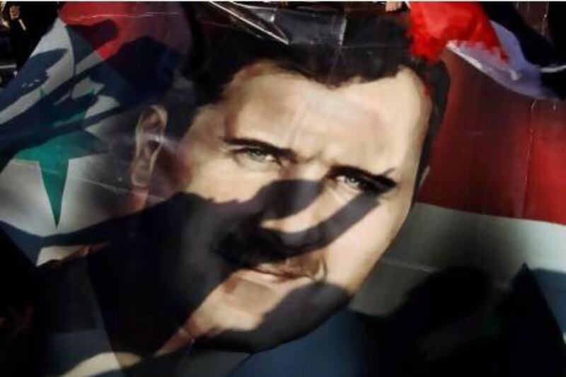 Shadows of Syrians are reflected on a giant poster showing President Bashar Assad, during a supporting rally in Damascus, Syria, Friday, Dec. 16, 2011. Syrian security forces opened fire on anti-government protesters after Friday prayers at several locations around the country, while the army sent reinforcements into a southern area where military defectors recently launched deadly attacks on regime troops.