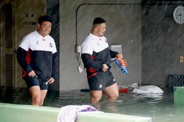 Japan players Takuya Kitade, left, and Yusuke Kizu wade through a flooded walkway at a stadium in Tokyo as Typhoon Hagibis hits the city. AP Photo