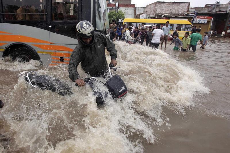 An Indian motorcyclist tries to balance himself as a bus drives past him on a flooded road after heavy rains in Ahmadabad. Ajit Solanki / AP Photo