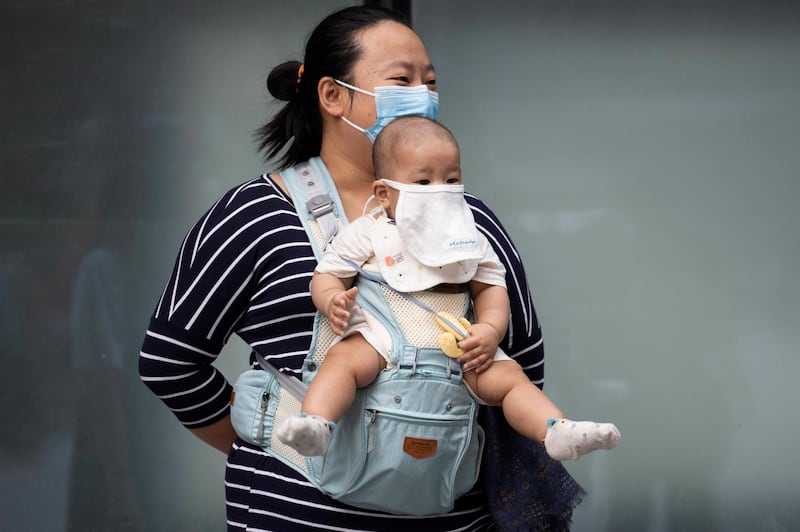 A woman and child wearing masks to help protect against the coronavirus stand out on the streets of Beijing. AP Photo