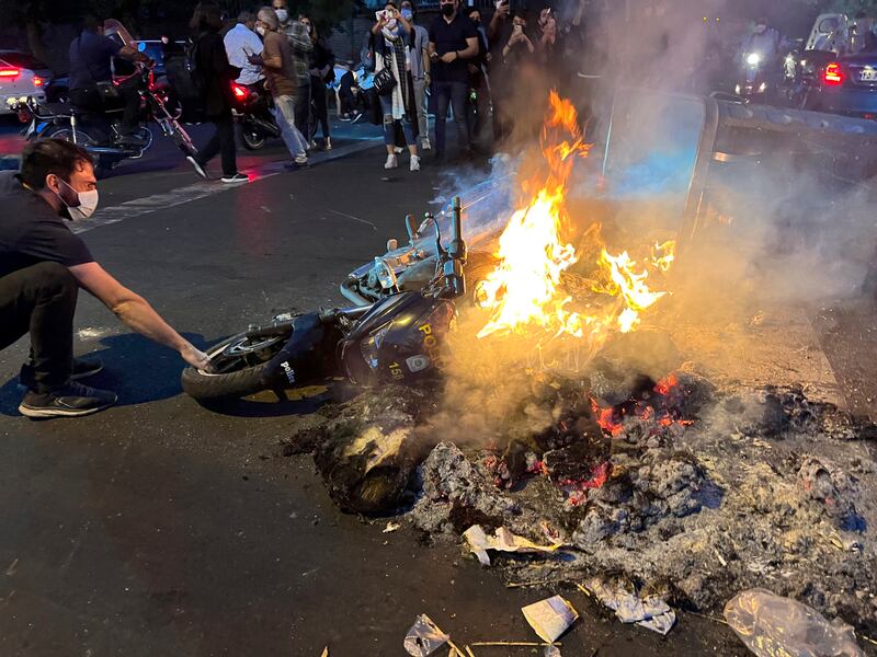 A man pulls out a police motorcycle set on fire during the protest. Amini had been detained for violating the country's conservative dress code. AP