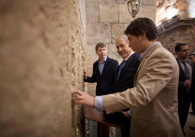 FILE - In this Jan. 22, 2013, file photo, Israeli Prime Minister Benjamin Netanyahu, center, prays with his sons Yair Netanyahu, left, and Avner Netanyahu at the Western Wall, the holiest site where Jews can pray in Jerusalem's old city. Facebook has blocked Israeli Prime Minister Benjamin Netanyahu's son Yair for 24 hours after he wrote a post criticizing the social media platform as "thought police" and sharing previously banned content. (AP Photo/Uriel Sinai, File)