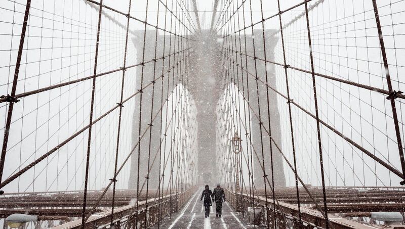 People shield themselves from the snow  as they cross the Brooklyn Bridge in New York. Justin Lane / EPA