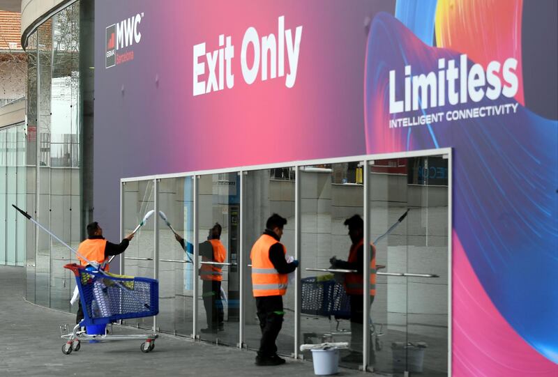 Workers clean glass doors at the Mobile World Congress MWC venue on February 12, 2020 at the Fira Barcelona Montjuic centre in Barcelona. Organisers of the World Mobile Congress were holding urgent talks today over the fate of the world's top mobile fair after a string of industry heavyweights withdrew over coronavirus, COVID-19, fears, a source close to the meeting said. / AFP / LLUIS GENE

