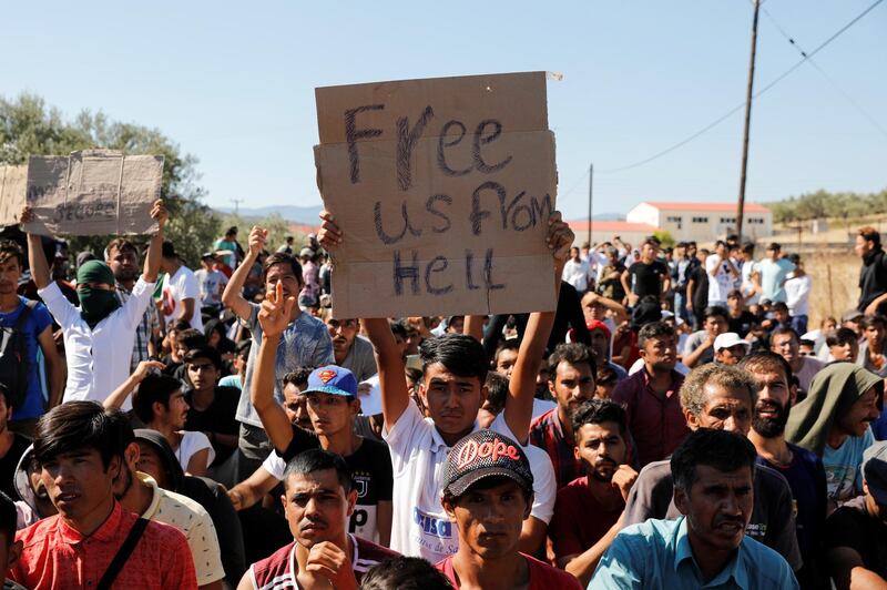 A migrant holds a placard as refugees and migrants take part in a demonstration against living conditions at the Moria camp on the island of Lesbos, Greece, October 1, 2019. REUTERS/Giorgos Moutafis