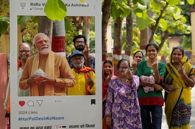 People show their fingers marked with ink from voting as they pose next to a cutout portrait of Prime Minister Narendra Modi in Varanasi, Uttar Pradesh. AP