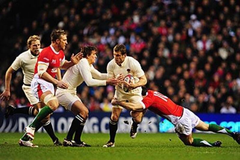 Mark Cueto, centre of England is tackled by Wales' Stephen Jones, right, during their opening Six Nations match.