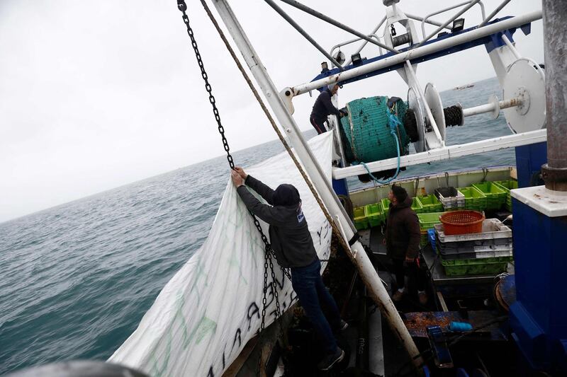 French fishermen hang a banner on their boat. AFP