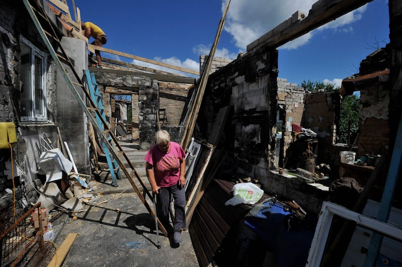 A woman's home is repaired by volunteers after being destroyed by shelling in the village of Zalissya. AFP