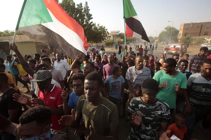 Sudanese protesters wave national flags during a rally. AFP