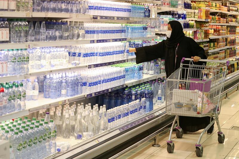 A Saudi woman, wearing a face mask, takes a bottle of water at a supermarket in Riyadh, Saudi Arabia. Reuters