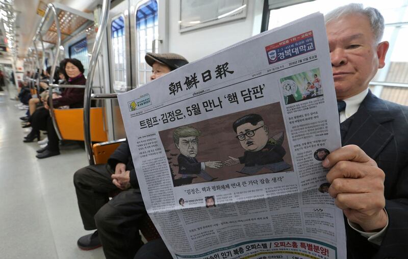 A passenger reads a newspaper with headline of a planned summit meeting between North Korean leader Kim Jong Un and U.S. President Donald Trump, left, at subway train in Seoul, South Korea, Saturday, March 10, 2018. The White House tried to swat away criticism Friday that the U.S. is getting nothing in exchange for agreeing to a historic face-to-face summit between President Donald Trump and North Korean leader Kim Jong Un. (AP Photo/Ahn Young-joon)