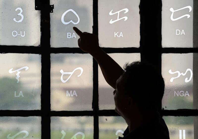 This photo taken on July 15, 2019 shows National Museum researcher Leo Batoon  pointing to a Baybayin character etched on a glass window at the National Museum in Manila.  From tattoos, shirts, and artworks to a computer font and mobile apps, Baybayin found a rebirth among millennials and professionals learning its 17 characters beyond the marginal mention in history class. 
 - TO GO WITH AFP STORY: Philippines-culture-language, FEATURE by Ayee MACARAIG
 / AFP / TED ALJIBE / TO GO WITH AFP STORY: Philippines-culture-language, FEATURE by Ayee MACARAIG
