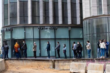 People wearing masks to protect themselves from the coronavirus pandemic wait to use ATM machines in Beirut. As the country faces a shortage of dollars, withdrawals have been cut to as little as $100 a week. AP