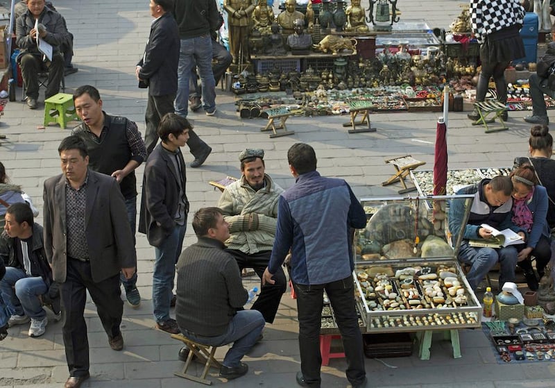 Uighur jade vendors wait for customers at an outdoor market where Chinese police have been checking their IDs daily since a vehicle attack in Beijing, Ng Han Guan / AP