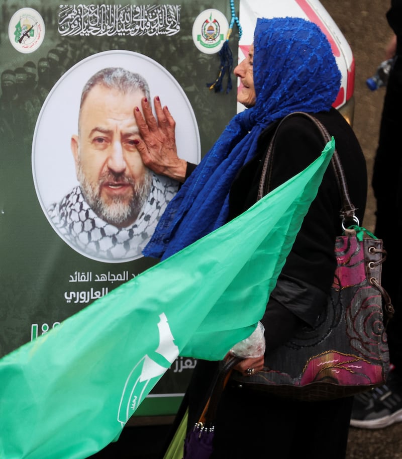 A woman mourns near a poster of Mr Al Arouri. Reuters
