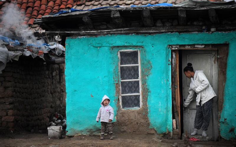 A Bulgarian Roma woman in front of a house with a child in the Roma district of the central Bulgarian town of Nikolaevo. Nikolay Doychinov / AFP Photo