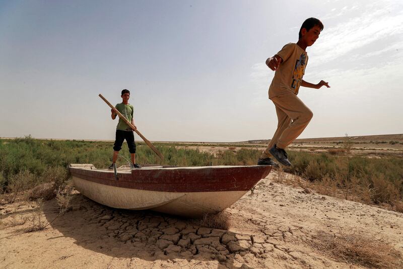 A boy holds an oar while another prepares to jump off a grounded boat on the soil of what was Lake Hamrine in Iraq's Diyala province. All photos AFP