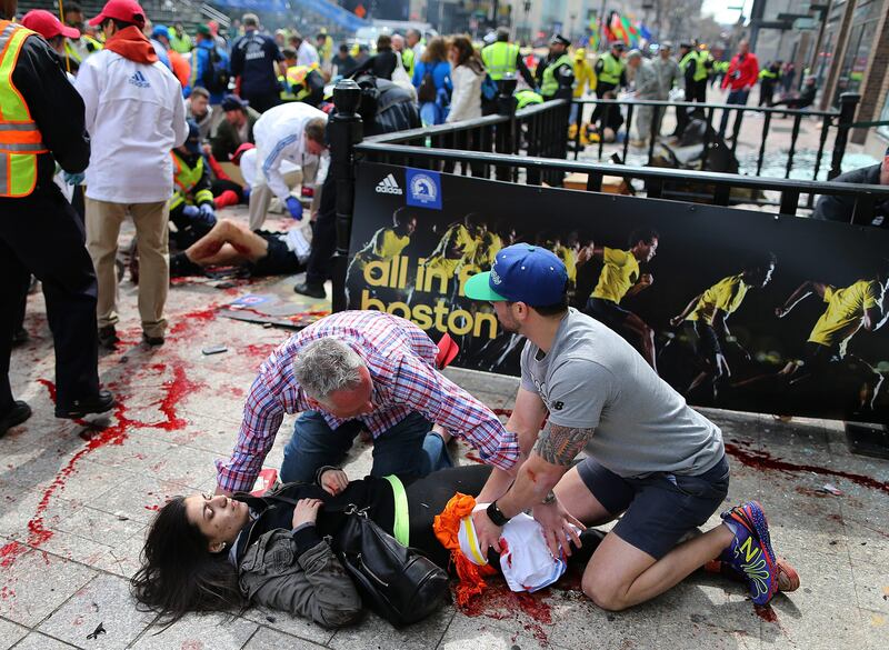 An injured woman is tended to at the finish line of the Boston Marathon,  in Boston, Monday, April 15, 2013. Two explosions shattered the euphoria of the Boston Marathon finish line on Monday, sending authorities out on the course to carry off the injured while the stragglers were rerouted away from the smoking site of the blasts. (AP Photo/The Boston Globe,  John Tlumacki) MANDATORY CREDIT; BOSTON OUT *** Local Caption ***  Boston Marathon Explosions.JPEG-07311.jpg